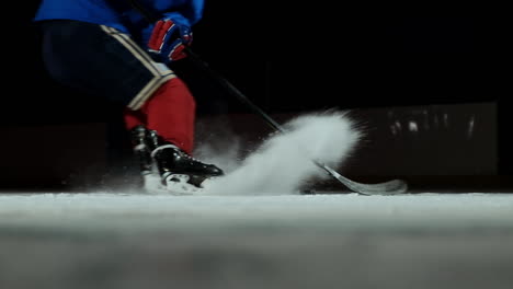 Close-up-slow-motion-hockey-puck-and-flying-snow,-hockey-player-picks-up-the-puck-stick